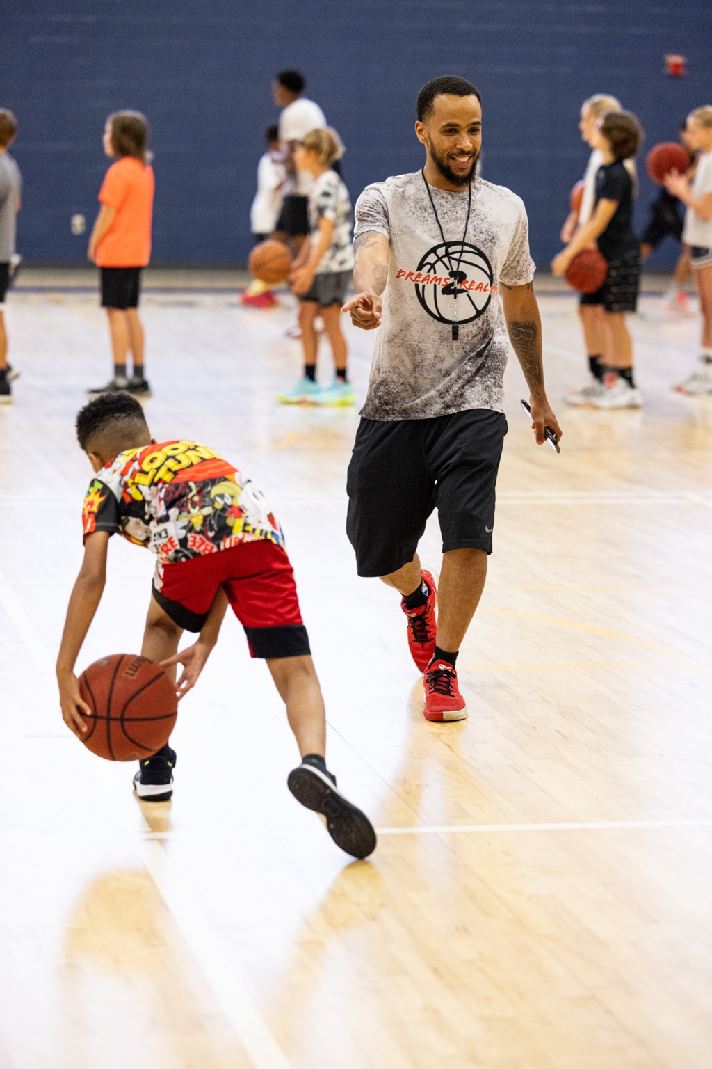 Coach Jeremy Malden guiding a young basketball player